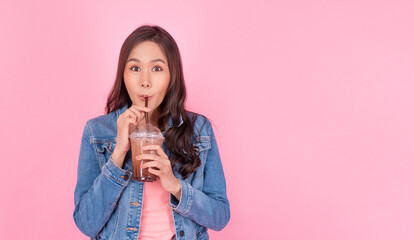 Cheerful asian woman drink ice cocoa with straw thirsty refreshment  looking camera on pink...