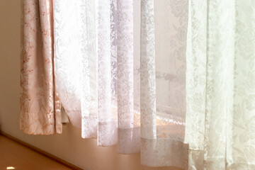 窓からの太陽光を遮る白のレースカーテン