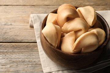 Tasty fortune cookies with predictions on wooden table, closeup. Space for text