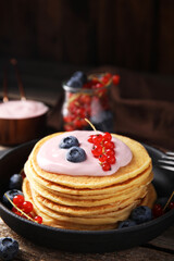 Tasty pancakes with natural yogurt, blueberries and red currants on wooden table