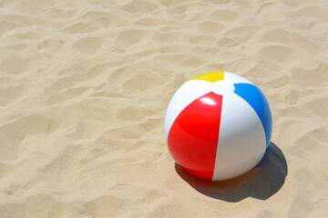 Colorful beach ball on sand, space for text