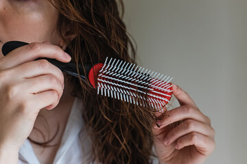 Woman's hands close-up brushing her wet hair with a brush for curly hair.