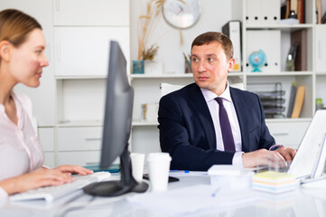 Focused adult successful man working with computer in modern office