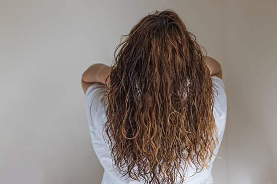 Brunette Woman Touching Long Wavy Hair, View From The Back.