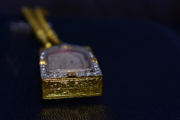 The golden Buddha amulet frame is shiny and placed on the ground.
