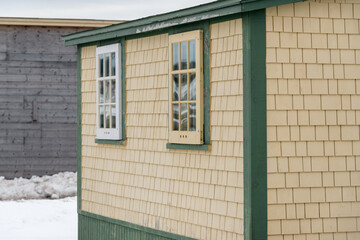 A vintage yellow cedar shake clapboard house with a grey shingled wooden roof. The building has two...