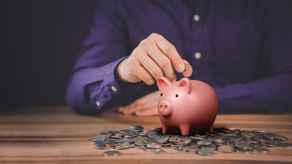 Man putting coin into piggy bank for saving money concept, business finance and investment.
