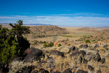 Landscape view of Granite Mountains of Wyoming with black boulders in foreground and blue sky with...