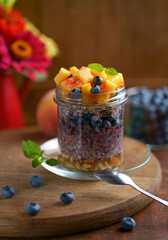 Obraz na płótnie Canvas Healthy blueberries and raspberries parfait in mason jars, scene on dark rustic background