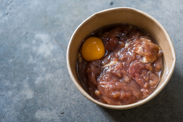 Closeup fresh marinated pork and egg ingredients for Thai style barbecue grill or Moo Krata