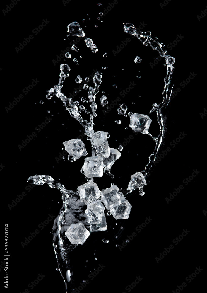 Wall mural Freeze motion of flying ice cubes with water splash isolated on black background.