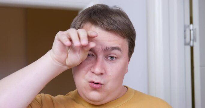 Emotional man grimaces doing something hard that requires a lot of effort. Finally he succeeds and wipes sweat from forehead with relief, but something goes wrong and he widened eyes