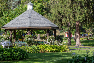Landscape texture background of a beautiful brown wooden gazebo, surrounded with landscaping in a...