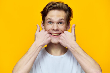portrait of a happy guy in a white t-shirt posing emotionally with fingers near his face