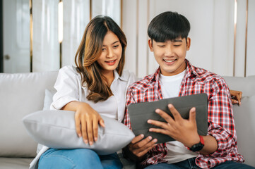 Young Asian couple enjoy with tablet together in living room