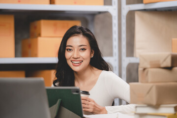online shopping concept, happy young Asian business owner woman prepare parcel box and check orders...