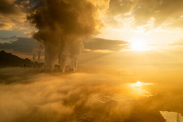 Aerial view coal power plant station in the morning mist, the morning sun rises. coal power plant and environment concept. Coal and steam. Mae Moh, Lampang, Thailand.