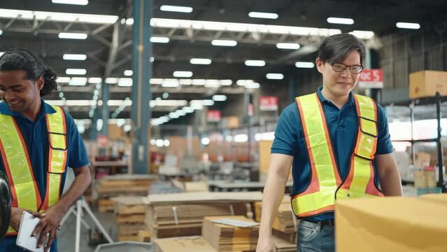 Warehouse worker signs electronic signature on tablet computer by hand while working inside a large distribution center, worker checking goods packages and making inventory of goods.