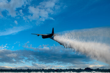 Plane dropping water against a cloudscape
