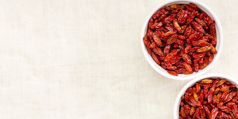 Dried Barberry berries in round ceramic white plates, top view on table. Ripe dry sour-tasting berries, healthy seasoning for food. Red Barberry natural food. Healthy and tasty spice