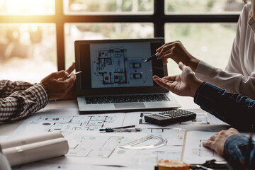 Project planning meeting engineers or architects drawing models working together using laptop...