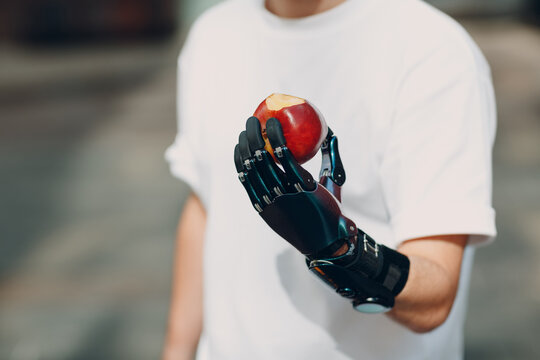 Cropped image of man with prosthetic hand holding a red apple