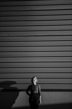 Grayscale photo of a woman standing beside wall