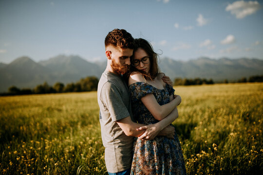 Man and woman hugging in green grass field