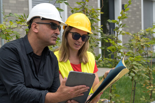 Man and woman with bump caps discussing work outdoor