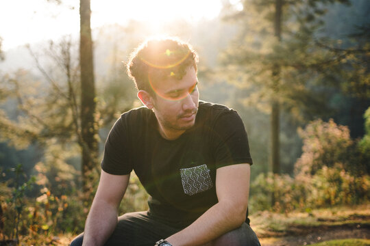 Man In Dark Shirt Sitting Near Trees