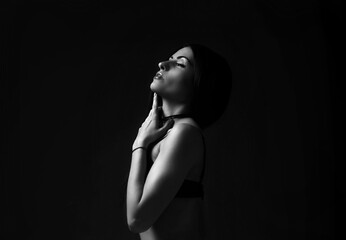 Monochrome photo of woman standing against dark background