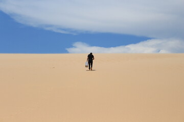 Fototapeta na wymiar Young man walking on the sand and looking for a sign - LOMAS DE ARENA SANTA CRUZ BOLIVIA