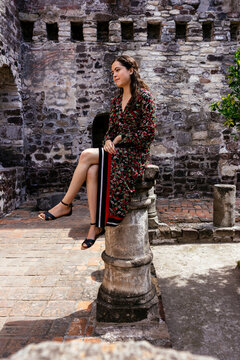 Woman in black and brown leopard print dress standing on gray concrete floor