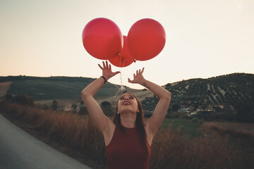 Woman in red tank top holding red balloons