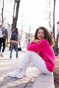 Woman In Red Long Sleeve Shirt And White Pants Sitting On Ground