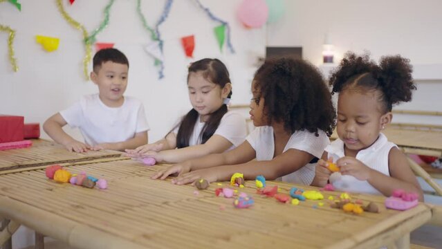 Group little asian and african american kids learning playing together sculpting plasticine create different shapes. Activity at home, pastime craft and hobby concept.