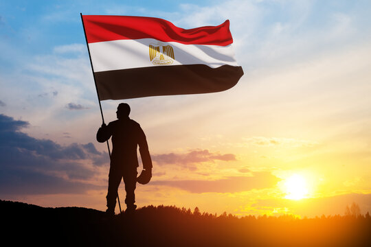 Silhouette Of A Solider with Egypt Flag Against the Sunrise in desert . Concept - armed forces of Egypt. Greeting card for Independence day, Memorial Day, Armed forces day, Sinai Liberation Day.