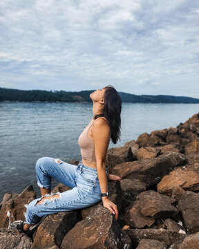 Young woman sitting on rocky shore of Washington Sea quest State Park Beach