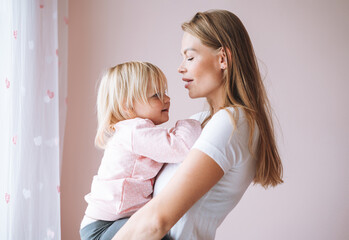 Portrait of young woman mother with baby girl daughter on hands at home