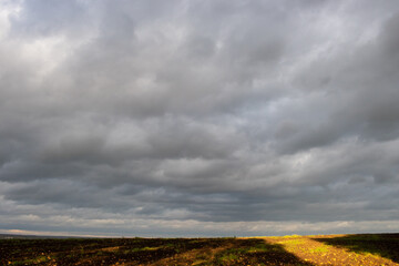 Autumn landscape with a plowed field and stormy dramatic sky. Clouds over the field