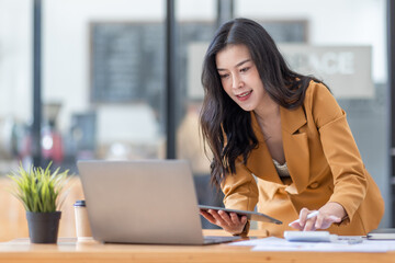 Business Asian woman using calculator for do math finance on Laptop, in workplace Office, business Working Financial, Business and Marketing Projects tax, accounting, statistics and analytic research 