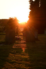 Grabsteine auf einem Friedhof bei Sonnenuntergang im Gegenlicht