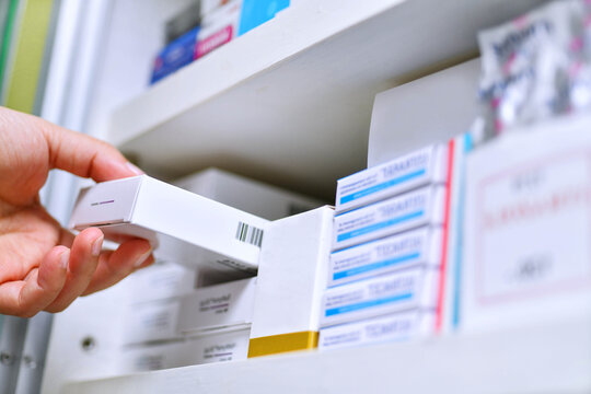 Closeup pharmacist hand holding medicine box in pharmacy drugstore.	