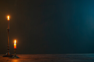 burning candles in vintage candlesticks on dark background