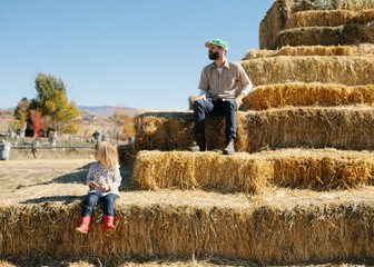 little girl and her father sitting on hay bales © Aubrey Westlund