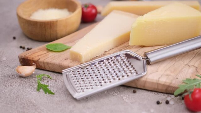 Pieces of parmesan hard cheese on a wooden cutting board at domestic kitchen