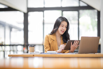 Obraz premium Asian businesswoman working in the workplace Office, Her is using touchpad while reading an e-mail on laptop and taking notes on the paper, accounting, tax, Financial, Business concept