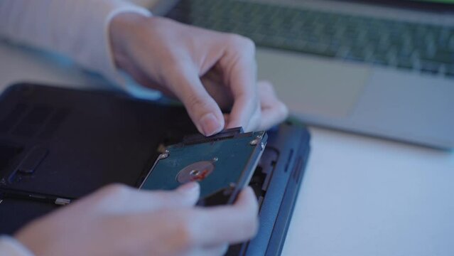 close-up Hand of woman installing or repairing hard disk on laptop computer.