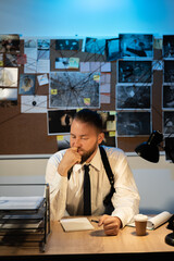 Serious thoughtful investigator or detective working at the desk in office, analyzing the...
