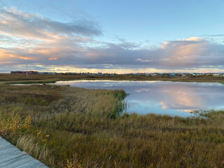 Fototapeta premium Walking on the boardwalk in Bethel with beautiful colors in the sky, on the water and on the tundra (September 2022)